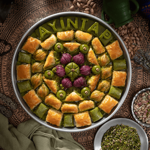 Ayıntap Baklava yazılı tepside karışık baklava ve fıstıklı tatlılar
