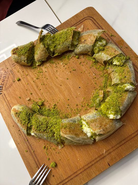 Katmerci Cengiz’de ahşap servis üzerinde dilimlenmiş Antep fıstıklı simit katmer