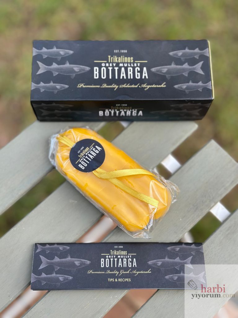 Trikalinos markasına ait kefal bottarga kutusu ve paketlenmiş ürünü. Sarı balmumu ile kaplanmış balık yumurtası, orijinal kutusu ve tarif önerileri broşürüyle birlikte sergileniyor.