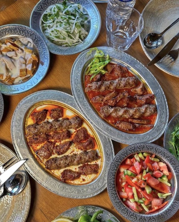 Ünal Et Lokantası’nda kebap tabakları, soğan ve salatalarla kurulan sofra